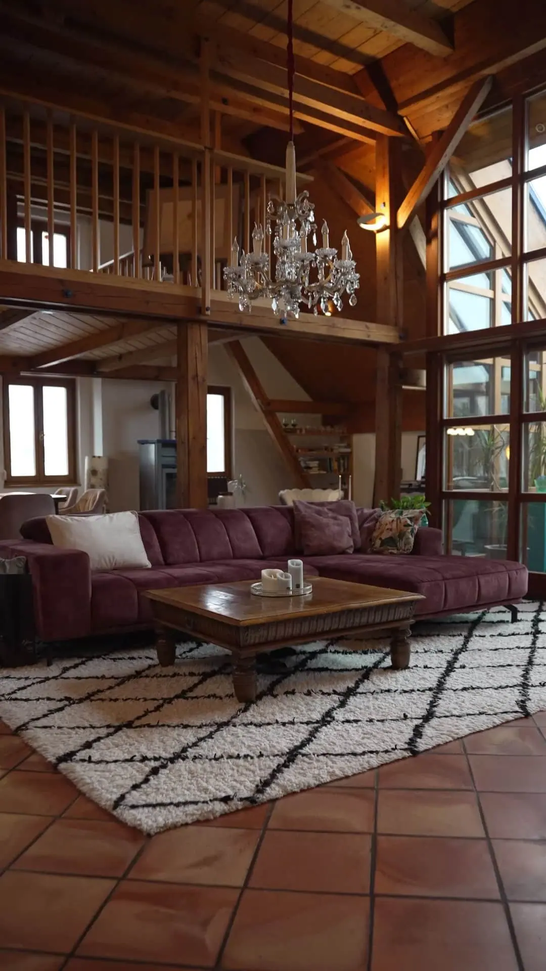 Wohnraum mit Kristallluster, Holzgalerie und Bordeaux-Sofa